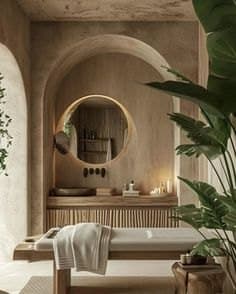 A treatment bed in a plaster room with an arched niche, a round mirror and a large potted plant
